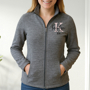Person wearing a gray zip-up jacket with a logo and text on a white background