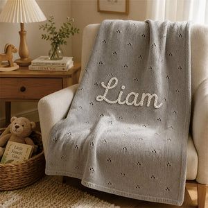 Gray pointelle knit blanket embroidered with Liam on an armchair