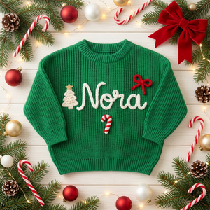 Personalized Christmas sweater with hand embroidered Christmas tree, bow & candy cane among Christmas decorations