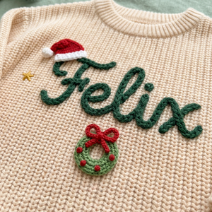 Close-up of hand embroidered santa hat & Christmas wreath on chunky knit