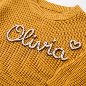 Close-up of hand embroidered chain stitch name on chunky knit