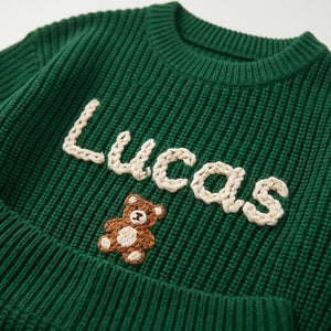 Close-up of hand embroidered chain stitch name on chunky knit