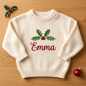 Machine embroidered holly name baby Christmas sweater, flat lay