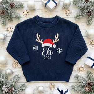 Machine embroidered reindeer antlers & Santa hat with year baby Christmas sweater among Christmas decorations