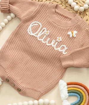 Pink knit baby romper embroidered with the name Olivia, a small flower and a butterfly