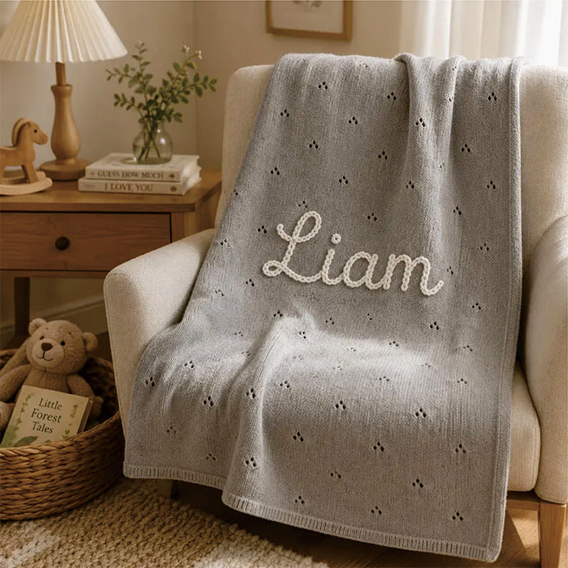 Gray pointelle knit blanket embroidered with Liam on an armchair