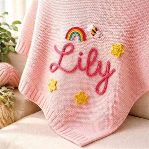 Pink knit baby blanket embroidered with Lily, a rainbow, a bee and stars