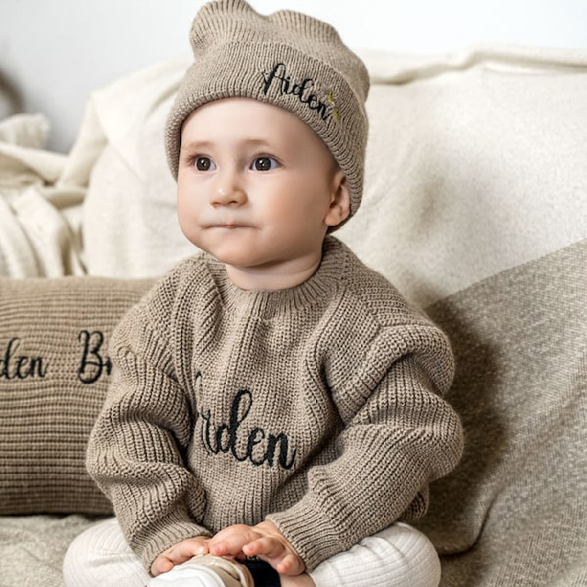 Baby wearing a chunky knit sweater with an embroidered name
