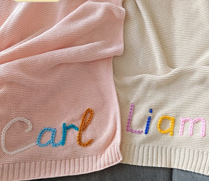 Pink and cream knit blankets embroidered with Carl and Liam in multicolor yarn