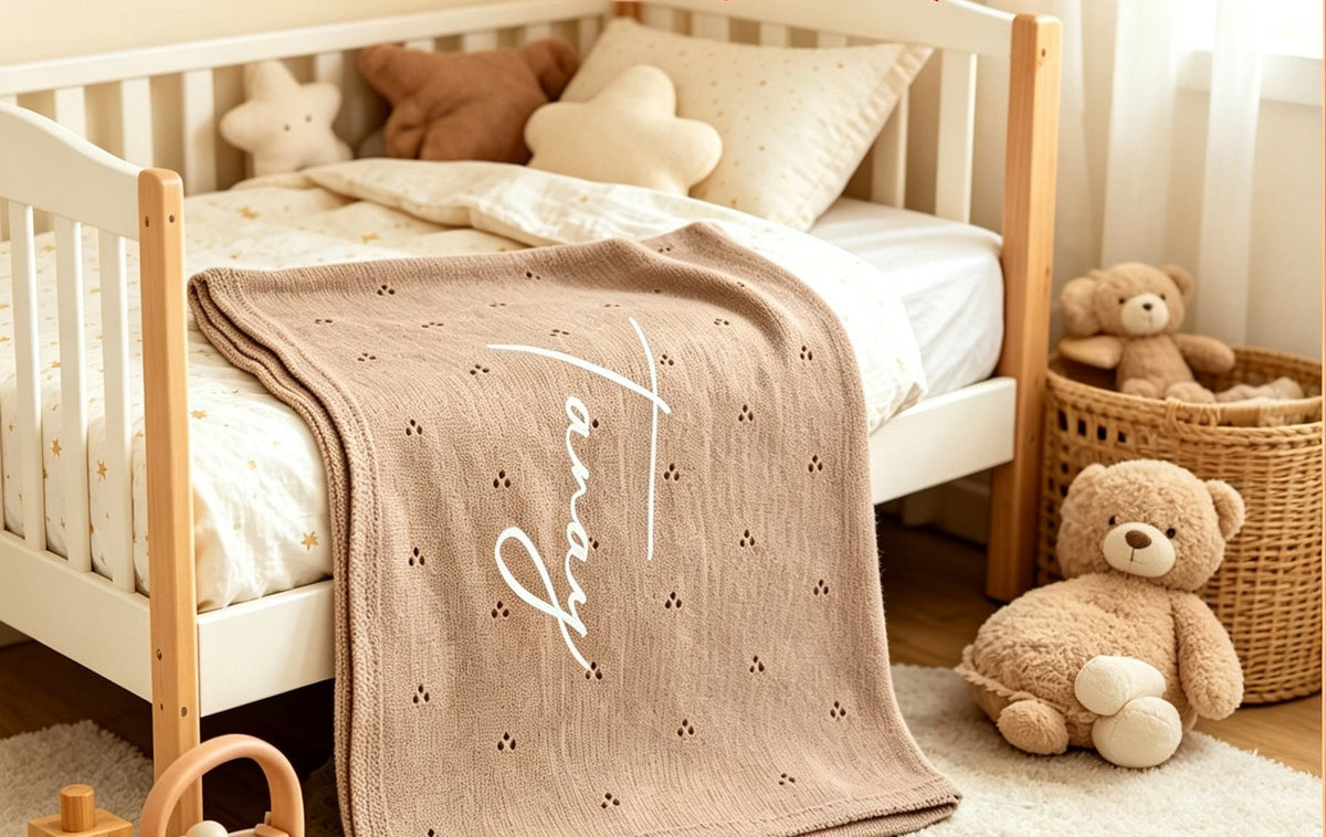 Tan pointelle blanket embroidered with Tanay on a toddler bed