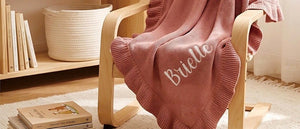 Rose pink ruffle blanket embroidered with Brielle on a chair