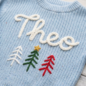 Close-up of hand embroidered three Christmas trees on chunky knit