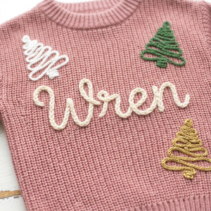Close-up of hand embroidered outline Christmas trees on chunky knit