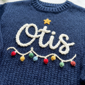 Close-up of hand embroidered Christmas string lights on chunky knit