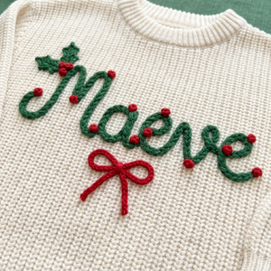 Close-up of hand embroidered holly berry name & bow on chunky knit