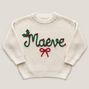 Hand embroidered holly berry name & bow Christmas sweater on a plain background