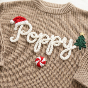 Close-up of hand embroidered santa hat, tree & peppermint on chunky knit