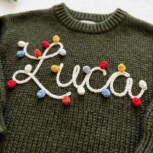 Close-up of hand embroidered string lights name on chunky knit