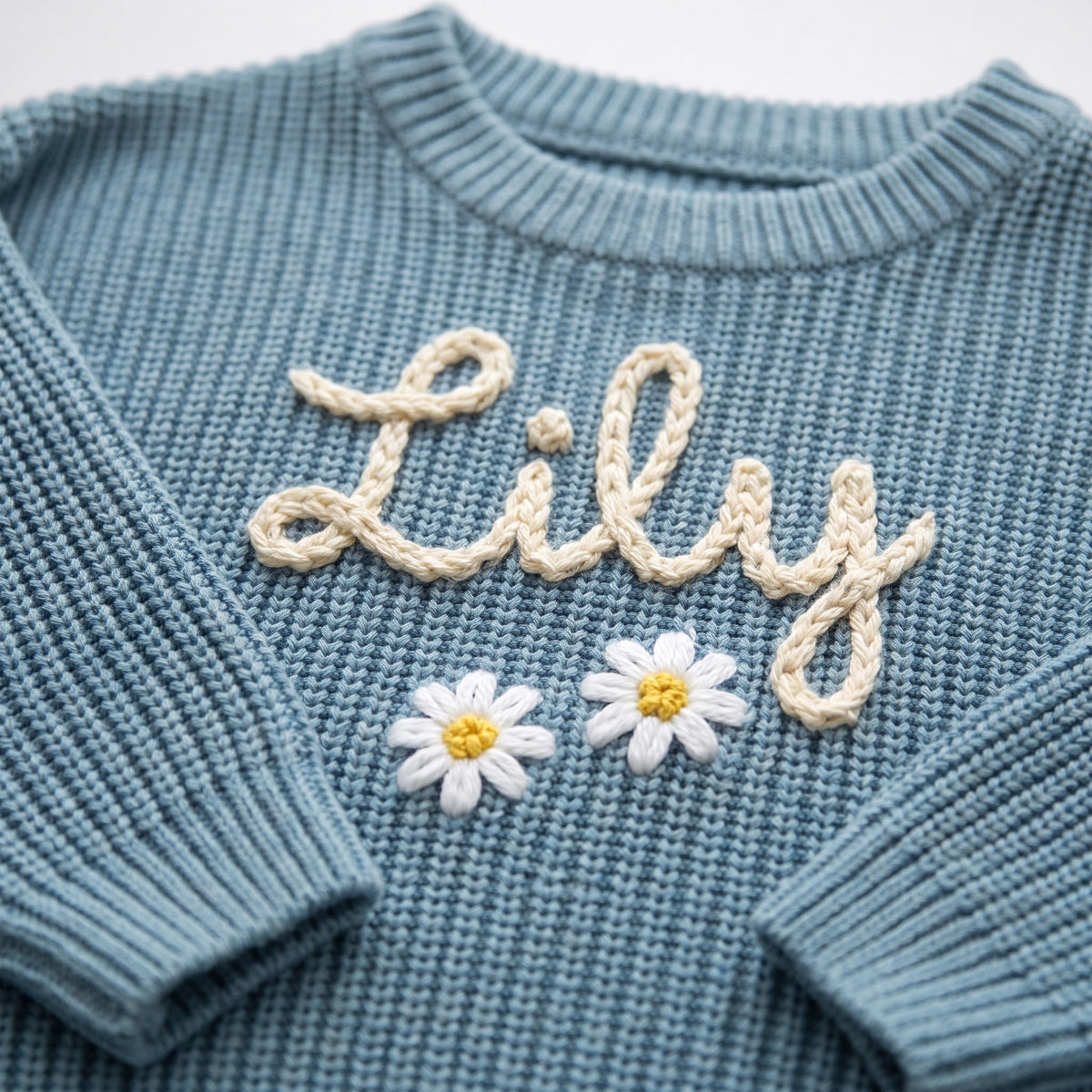 Close-up of hand embroidered chain stitch name on chunky knit