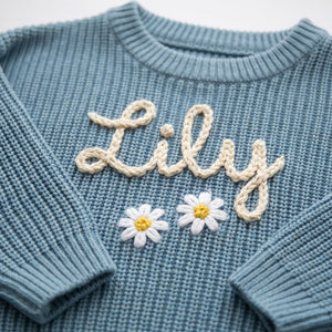 Close-up of hand embroidered chain stitch name on chunky knit