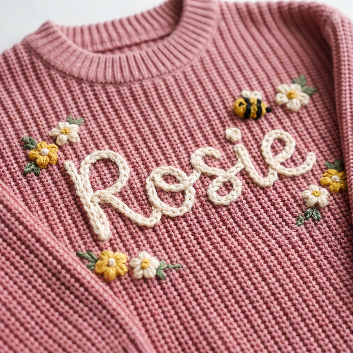 Close-up of hand embroidered chain stitch name on chunky knit