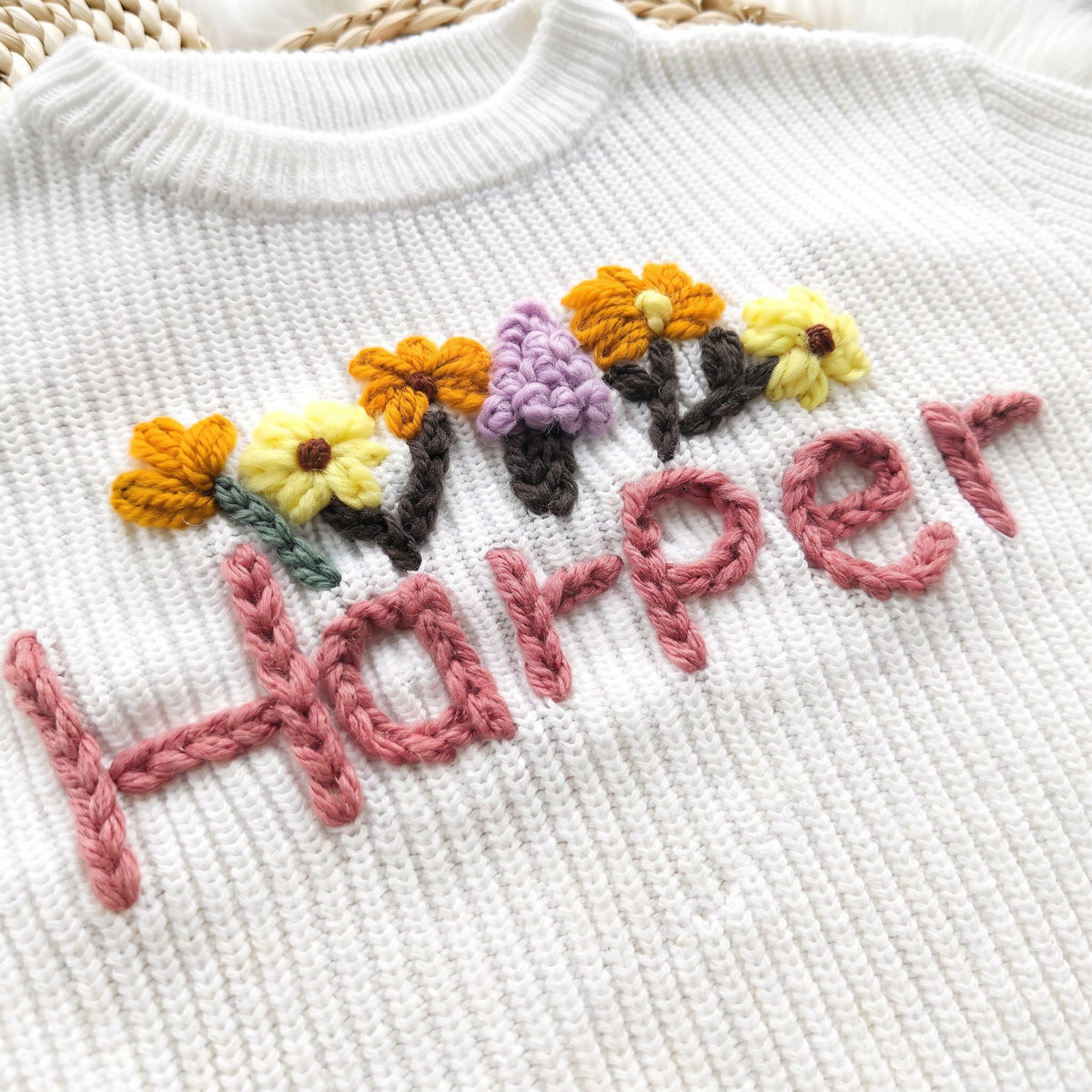 Close-up of hand embroidered chain stitch name on chunky knit