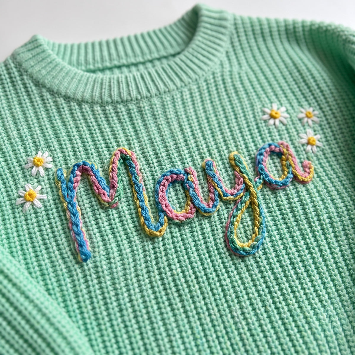 Close-up of hand embroidered chain stitch name on chunky knit