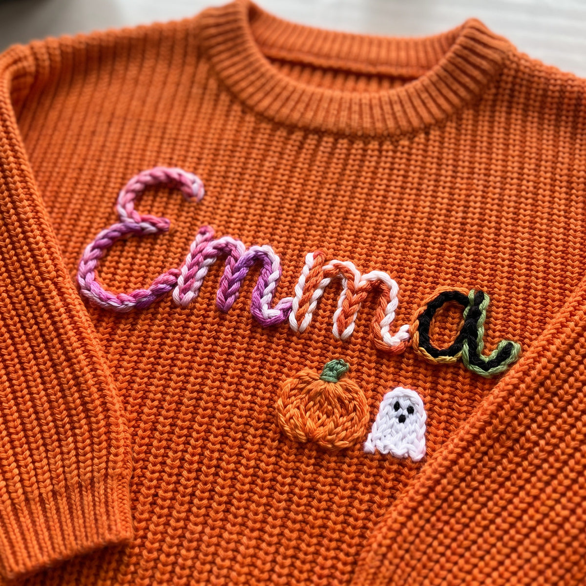 Close-up of hand embroidered chain stitch name on chunky knit