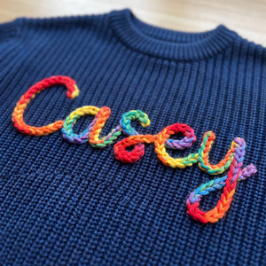 Close-up of hand embroidered chain stitch name on chunky knit