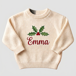 Machine embroidered holly name baby Christmas sweater on a plain background