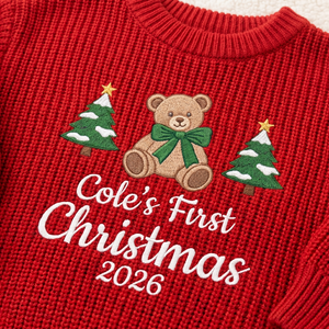 Close-up of machine embroidered first Christmas teddy bear on chunky knit