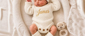 Newborn in a cream knit romper embroidered with the name James