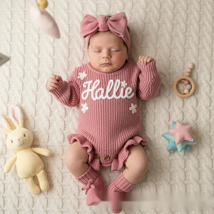 Newborn in a rose pink ruffle knit romper embroidered with the name Hallie