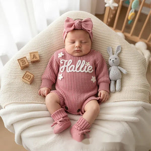 Baby resting in a rose pink knit romper embroidered with Hallie and daisies