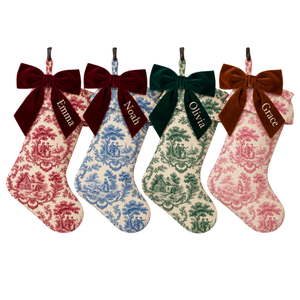 Set of four personalized toile Christmas stockings with ruffle top and velvet bow in red, blue, dark green and pink